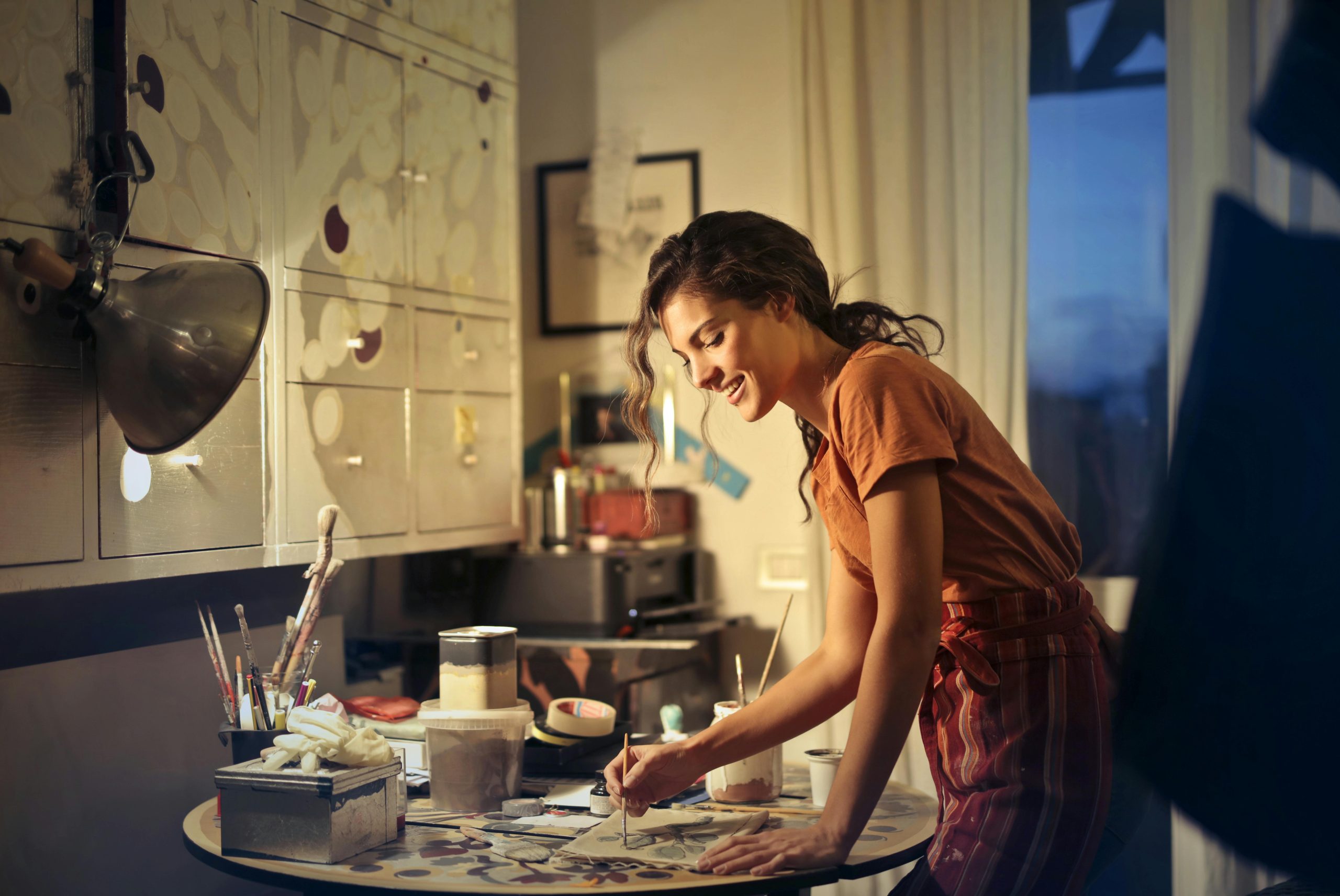 Woman working at a desk in a modern creative office, surrounded by mood boards and hanging lightbulbs.